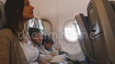 在长时间的飞机飞行中，年轻漂亮的母亲和两个无聊的孩子一起去度假。