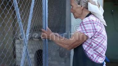 老妇人把铁门关到他的院子里。 东欧，可怜的养老金领取者，手上有皱巴巴的皮肤