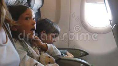 两个小无聊的孩子在长时间的飞机飞行中环顾四周，和家人一起去度假。