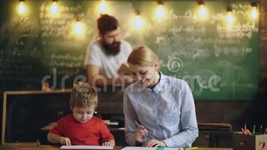 一个女人和一个<strong>男</strong>孩在学校教室里画画，背景是一个<strong>男</strong>人读一本书。 <strong>男</strong>孩画<strong>老师</strong>