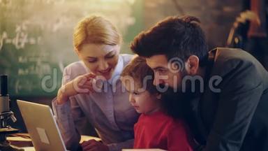 家里用笔记本电脑的家人。 快乐的年轻家庭一起在笔记本电脑上看卡通。 家庭时光快乐。 家庭观念。