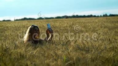 一个苗条的女人走在麦田上，在阳光明媚的夏<strong>日</strong>在<strong>手机</strong>上拍照小穗。