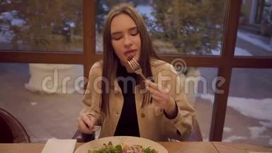 一个可爱的女孩在餐馆吃饭的肖像。 女士喜欢吃一道美味的新鲜蔬菜和
