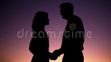一对已婚夫妇在夕阳渐变的背景下拥抱的剪影