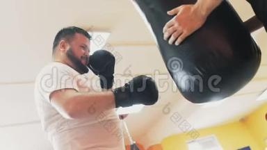 健身和健康。 在健身房拳击。 一个胖子和私人教练在运动场上打拳。 个人减肥