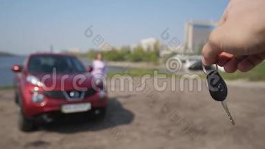 镜头前，一个男人挥动一把汽车<strong>钥匙</strong>，一个快乐的女孩跑<strong>起来</strong>，拿着它跑到车上。 4K慢慢