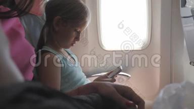 可爱的女孩乘飞机旅行，在飞行中使用数字平板电脑。 与孩子一起出国旅行的概念。