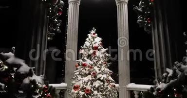 神奇的圣诞树在露台上覆盖着雪，晚上街道上有柱子。