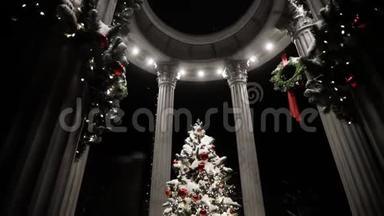 在神圣的夜晚，用柱子覆盖着雪装饰在凉亭里的圣诞树。