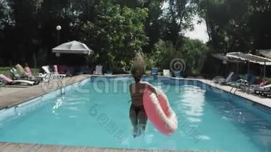 暑假，一个带充气橡胶圈的年轻女子跳进了清澈的蓝色游泳池里