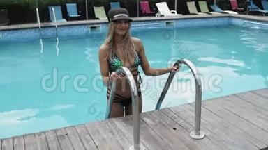 穿泳衣的女士，帽子和太阳镜从游泳池里出来
