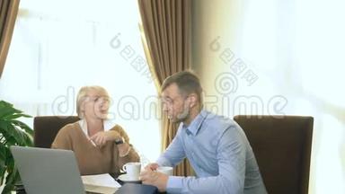 男人和女人坐在办公室，手提电脑前说话