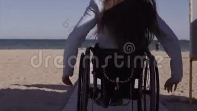 轮椅上的年轻残疾妇<strong>女</strong>在<strong>春季</strong>或<strong>春季</strong>在靠近海边的木制坡道旁为残疾人移动