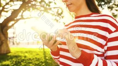 在户外对着夕阳使用智能手机的女人