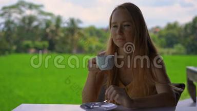 一位年轻女子在一家有稻田背景的乡村咖啡馆喝茶或咖啡的特写镜头