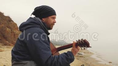 这位戴着针织帽子的人坐在石头上<strong>弹吉他</strong>。从上面<strong>弹吉他</strong>