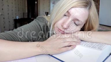 疲惫的女人坐在桌子旁<strong>睡觉</strong>，头上戴着一本大书，教育和<strong>学习</strong>观念