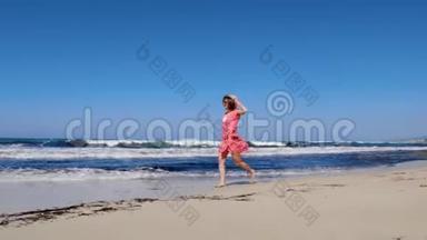 年轻的白种人女子赤脚在沙滩上奔跑，把帽子扔在天空中。 她穿着红色连衣裙和太阳镜