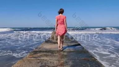 年轻女子赤着脚走在海上码头上，而海浪<strong>撞<strong>击</strong>码头。 <strong>后</strong>面的镜头。
