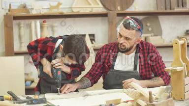 少年男孩帮助他父亲在木板上<strong>钻洞</strong>。