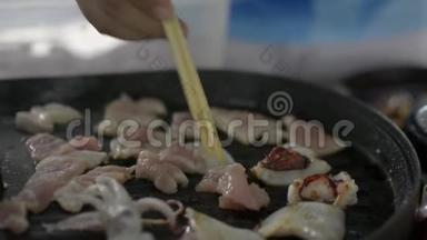 生猪肉和鱿鱼在锅里烤着。 煮肉。
