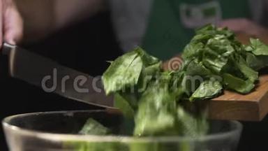 厨师把切碎的菠菜从木板上倒入玻璃碗里，做蔬菜沙拉，用