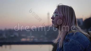 美丽的红日落在河上。 女孩坐在水边，望着远处。 美丽的电影框架。