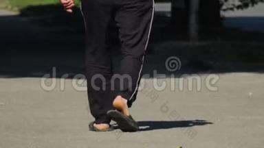 一个男人穿着黑色<strong>运动裤</strong>和拖鞋走在街上。