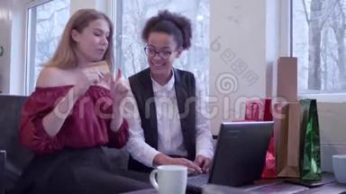 网上购物，微笑的多民族朋友女孩用塑料卡和笔记本电脑进行网上购物