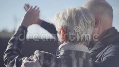 一位白发苍苍的女人的背影，一位秃头男人的背影，站在外面，双手合拢，一张来自烈阳的脸
