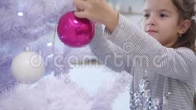漂亮的小女孩从模糊的背景走到圣诞树的最前面，在一棵树上放了一个玻璃美人