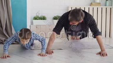 活泼英俊的父亲和他快乐的儿子正在家里的木地板上一起锻炼。 幸福家庭