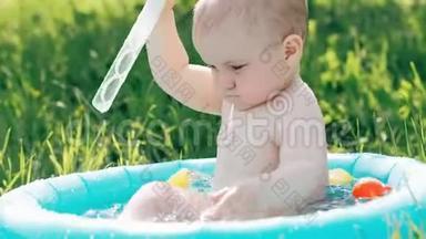 夏天，小男孩在草坪上的充气游<strong>泳池里玩耍</strong>和泼水
