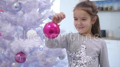 可爱的孩子玩一个粉红色的宝布尔，<strong>左右摇摆</strong>，站在圣诞树附近，微笑。