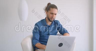 进步的<strong>自由</strong>职业者工作与笔记本电脑坐在扶手椅在<strong>舒适</strong>和轻的办公室。