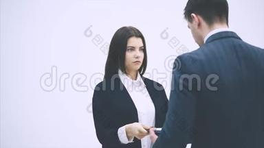 可爱的办公室女人正在向她的老板汇报。 但他很严格，批评她，指着剪贴板。