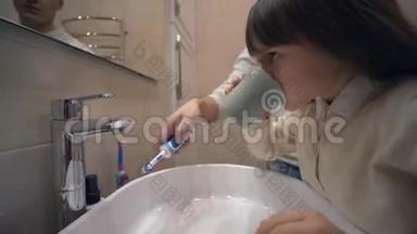 儿童口腔卫生，可爱的小女孩刷牙，用干净的自来水冲洗洗手池上的嘴