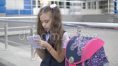 在学校大楼附近穿校服的女孩<strong>放学</strong>后在笔记本上写一些东西。