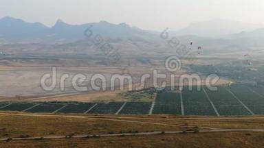 几架滑翔伞正在日落谷上空飞行，夏季空中无人驾驶飞机上的葡萄园和山脉就在地平线上