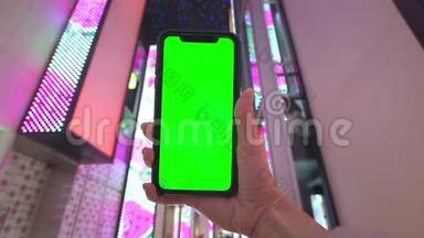 一只手握着一部智能手机，<strong>手机背景</strong>是拉斯维加斯一家购物中心的霓虹灯