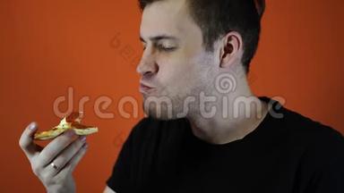 男人吃披萨，特写橙色背景。 男人享受美味的饭菜