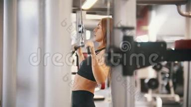 一名运动员女子在健身房训练-把酒吧拉到身体-训练双手