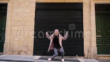 有趣的少女穿着羽绒服在城市车库的背景下跳舞。 街头，人们，<strong>平凡</strong>的日子