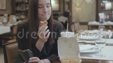 年轻漂亮的女人坐在昂贵的餐馆里，用可口可乐吃鸡块