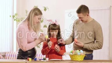 <strong>一家人</strong>带着<strong>女儿</strong>，家里装饰的复活节彩蛋摆在桌子上是颜料和一篮子彩蛋..
