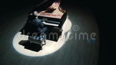 舞台上的大<strong>钢琴</strong>：一个穿着黑色西装的<strong>优雅</strong>男子在音乐厅的舞台上演奏大<strong>钢琴</strong>