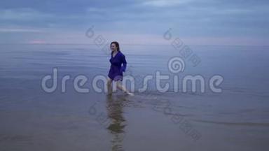 年轻的红发女子穿着蓝色连衣裙，湿发在<strong>水</strong>面上行走，<strong>溅起水</strong>花-忧郁而寒冷的日落