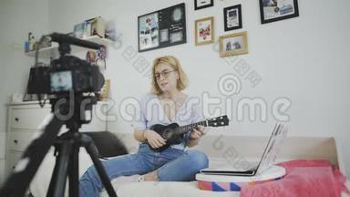 年轻迷人的女孩时尚博主正在用相机录制视频、唱歌和弹吉他