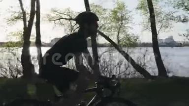 带胡子的年轻骑自行车的人穿着黑色的衣服喝水。 在<strong>沿河</strong>公园骑自行车轻松恢复。