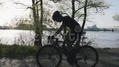 骑自行车时，骑自行车的人从水瓶里喝水。 口渴的骑自行车的人骑在城市公园<strong>沿河</strong>。